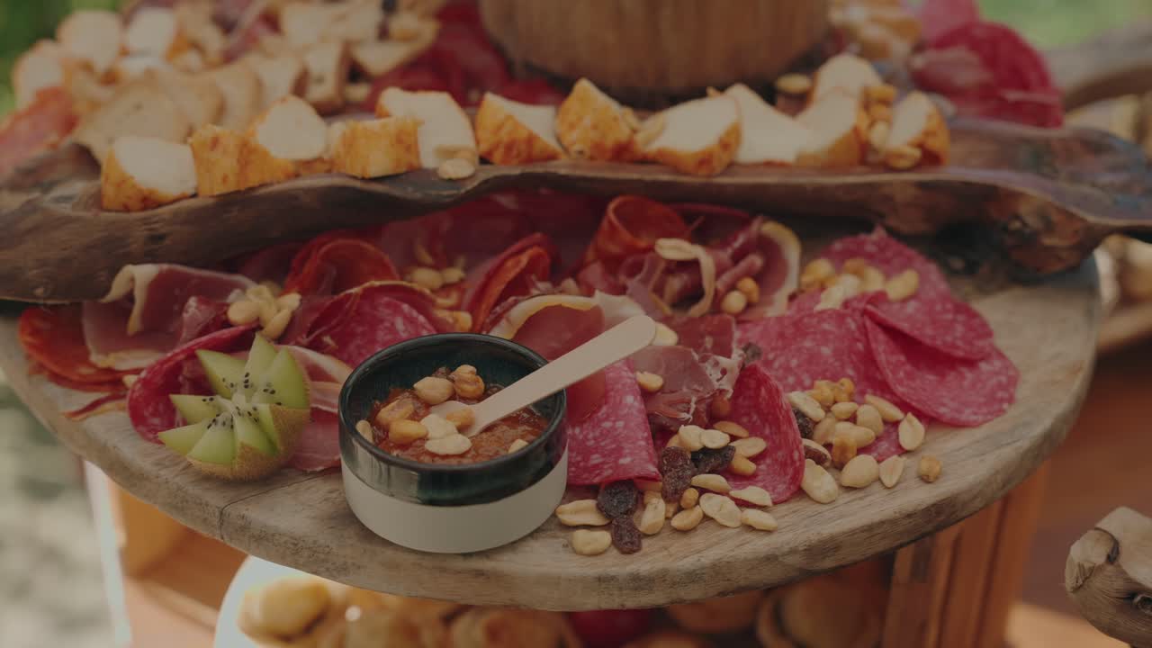 Rustic charcuterie platter featuring assorted cured meats, cheese cubes, nuts, and dipping sauce