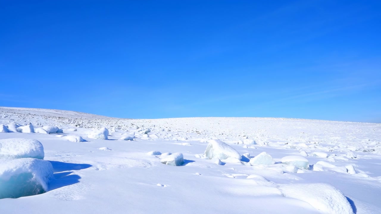 鮮やかな青空の下の雪のツンドラ。丸い氷の小丘が点在する広大なパノラマの凍った風景。