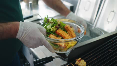 the cook is taking another ingredients for adding the salad