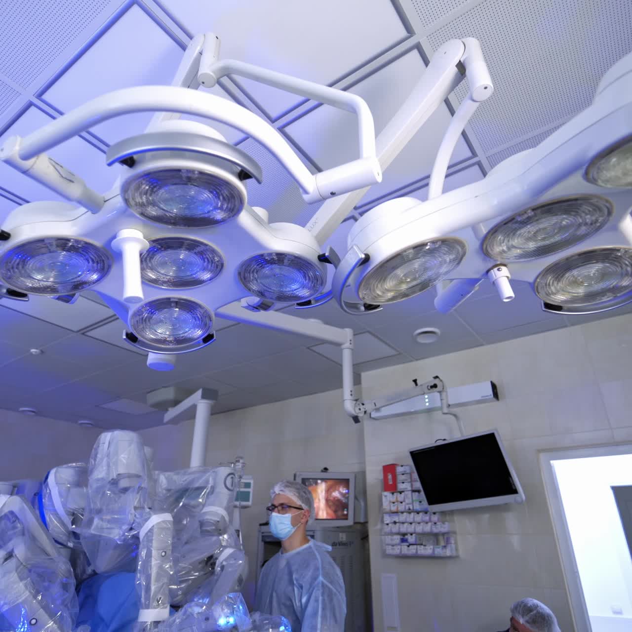 Surgery with modern robotic equipment. Medical machine with robotic arms performing an operation. Doctor in medical uniform near futuristic surgical robot.