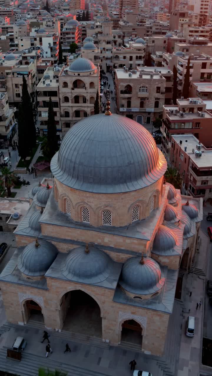 Gün batımında hareketli bir şehir manzarasını yakalayan hava videosu, kentsel mimariyi ve şehrin canlı atmosferini öne çıkarıyor.