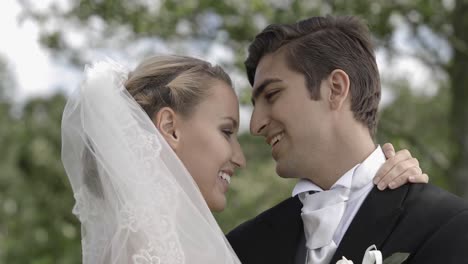 groom kissing his pretty new wife in a park