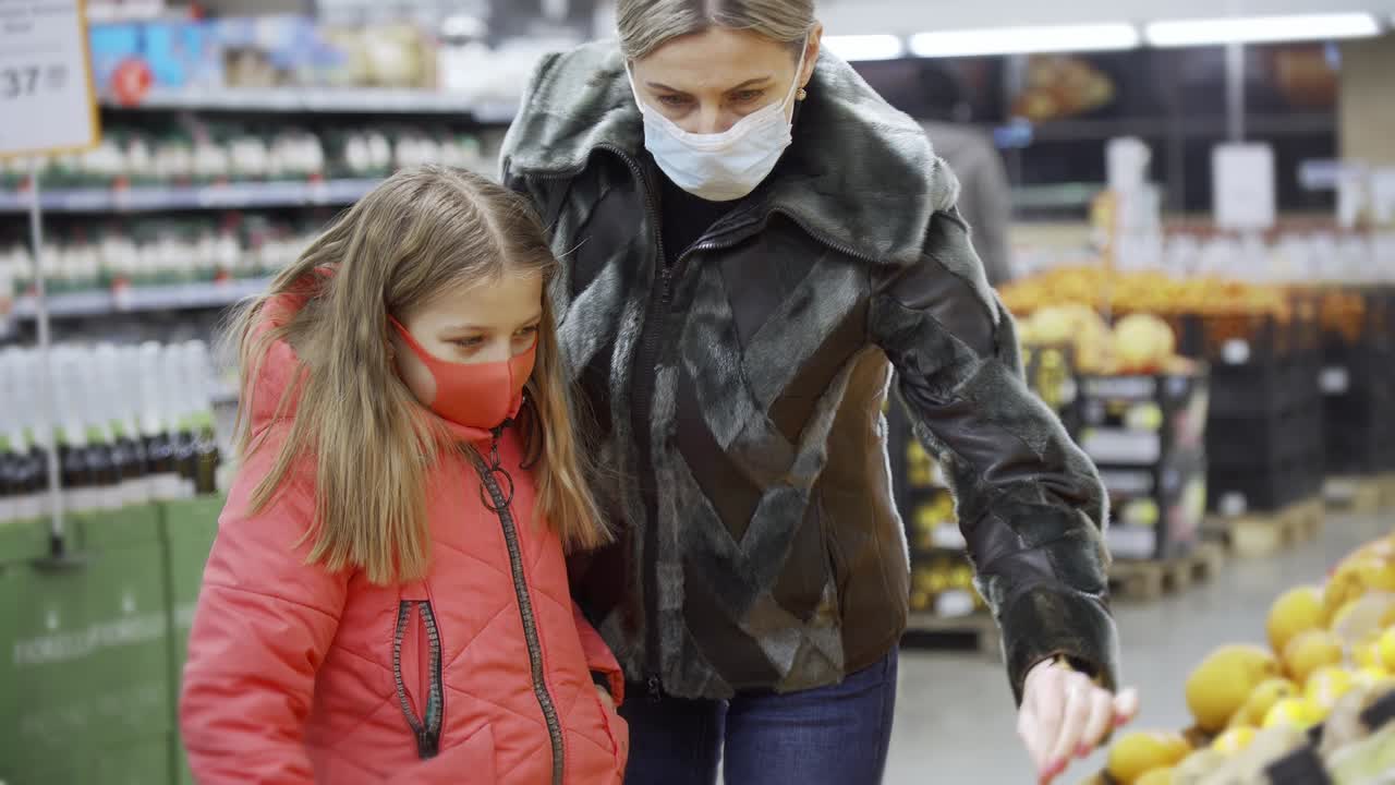 mamá e hija en la tienda de comestibles eligen verduras para comprar. consideran cuidadosamente la calidad de las verduras.