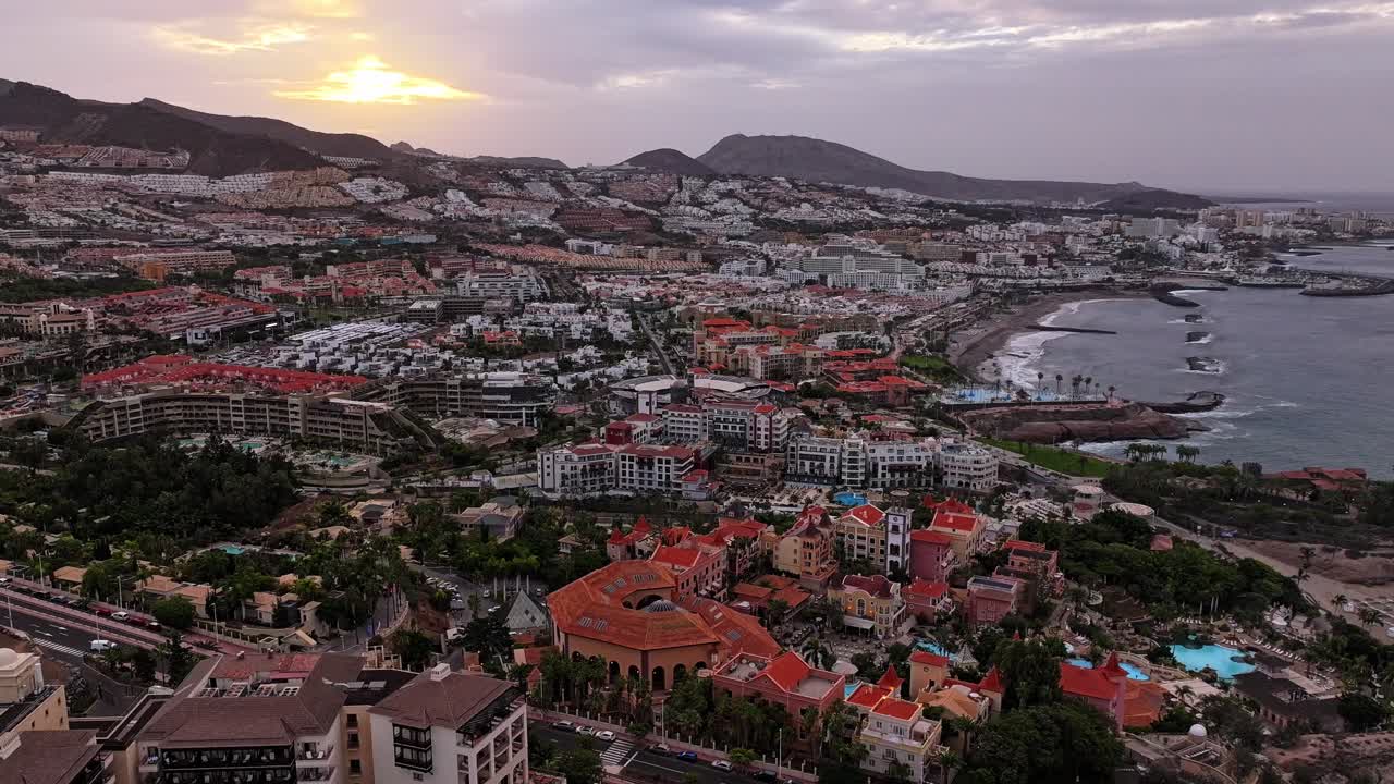 Vibrant sunrise hyperlapse paints Costa Adeje skyline, oceanfront luxury resorts