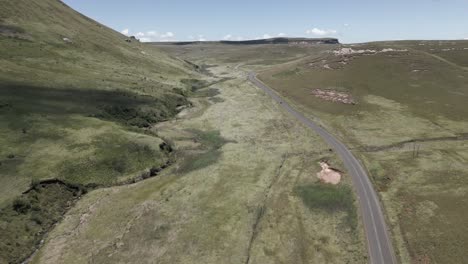 Aerial-follows-car-on-highway-in-South-Africa-through-grassland