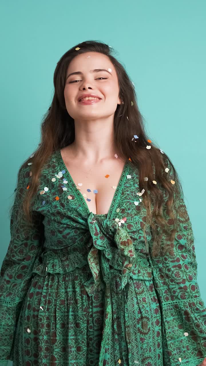 Cheerful young woman dancing under falling confetti