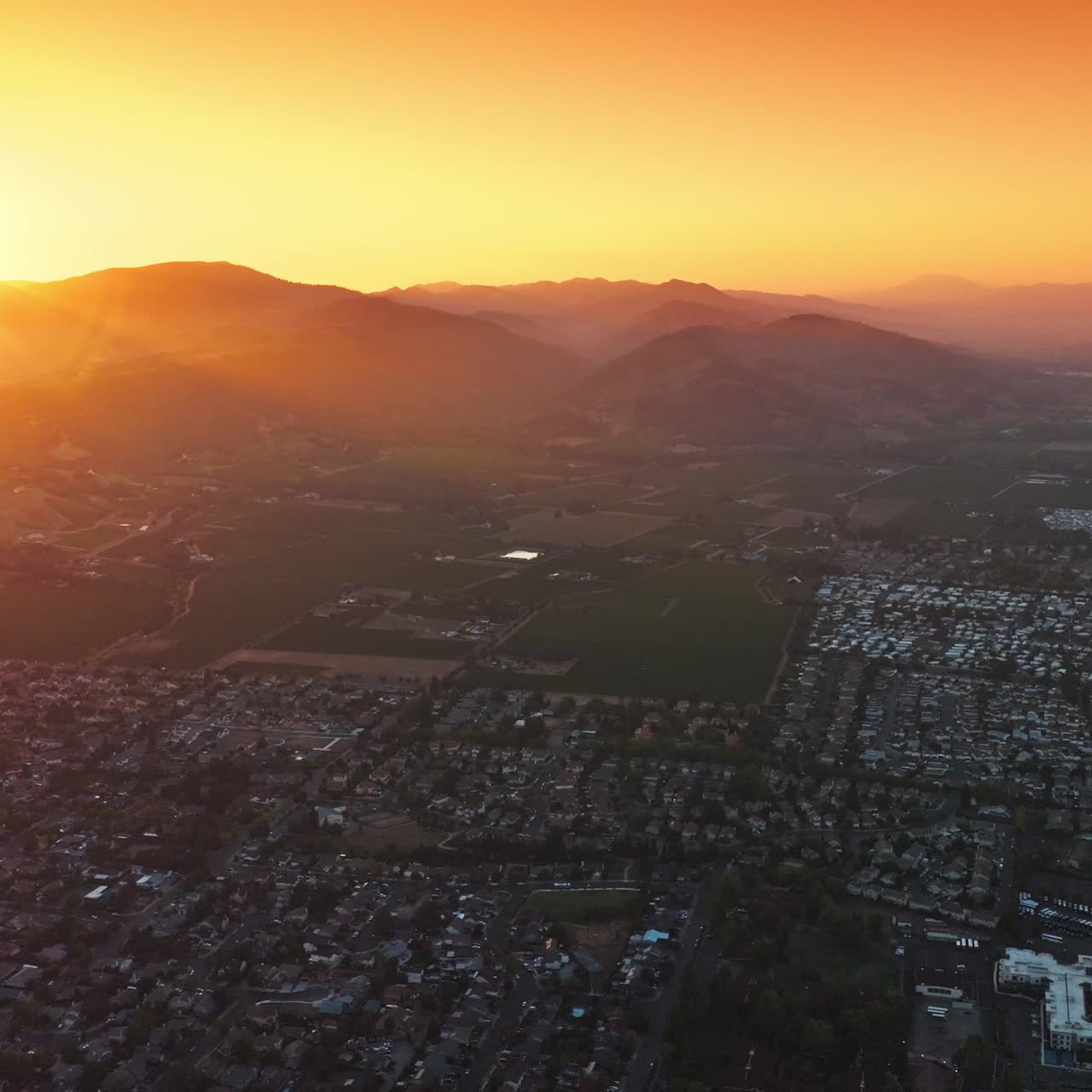 Panorama of the city surrounded by agricultural fields. Beautiful scenery of Napa, California, USA at setting sun. Orange sky at backdrop