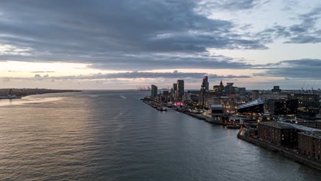 River Mersey, Liverpool riverside at dusk, city skyline, Pier Head, and moving clouds, England, UK. Aerial drone, Time-lapse motion-lapse