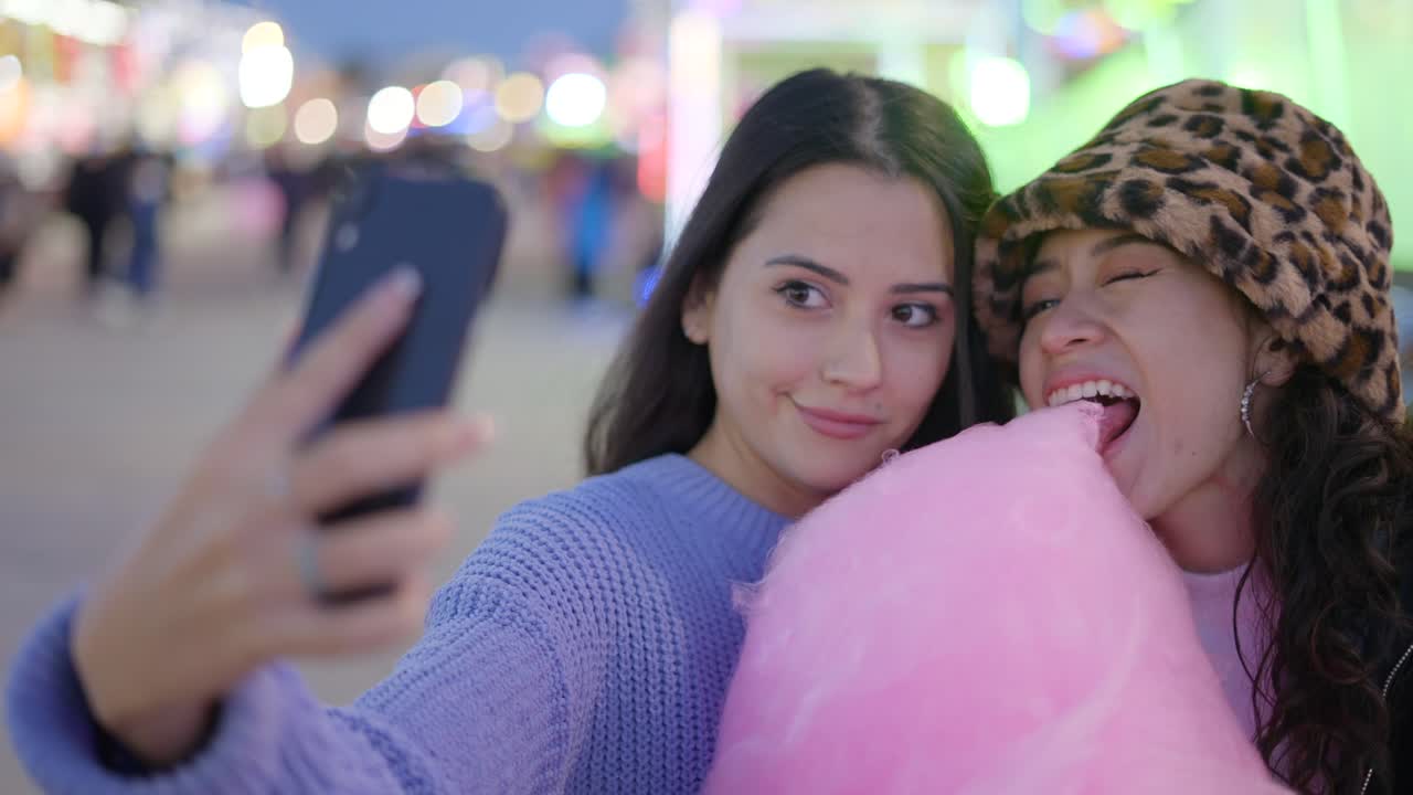 Two Friends Taking a Selfie at a Fair with Cotton Candy