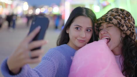 two friends taking a selfie at a fair with cotton candy