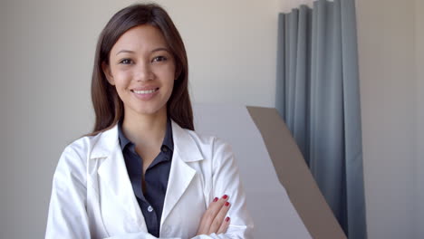 Portrait-Of-Female-Doctor-Wearing-White-Coat-In-Exam-Room