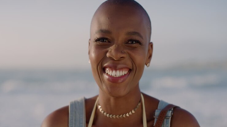 close up portrait of happy african american woman laughing enjoying summer vacation on warm sunny beach background slow motion