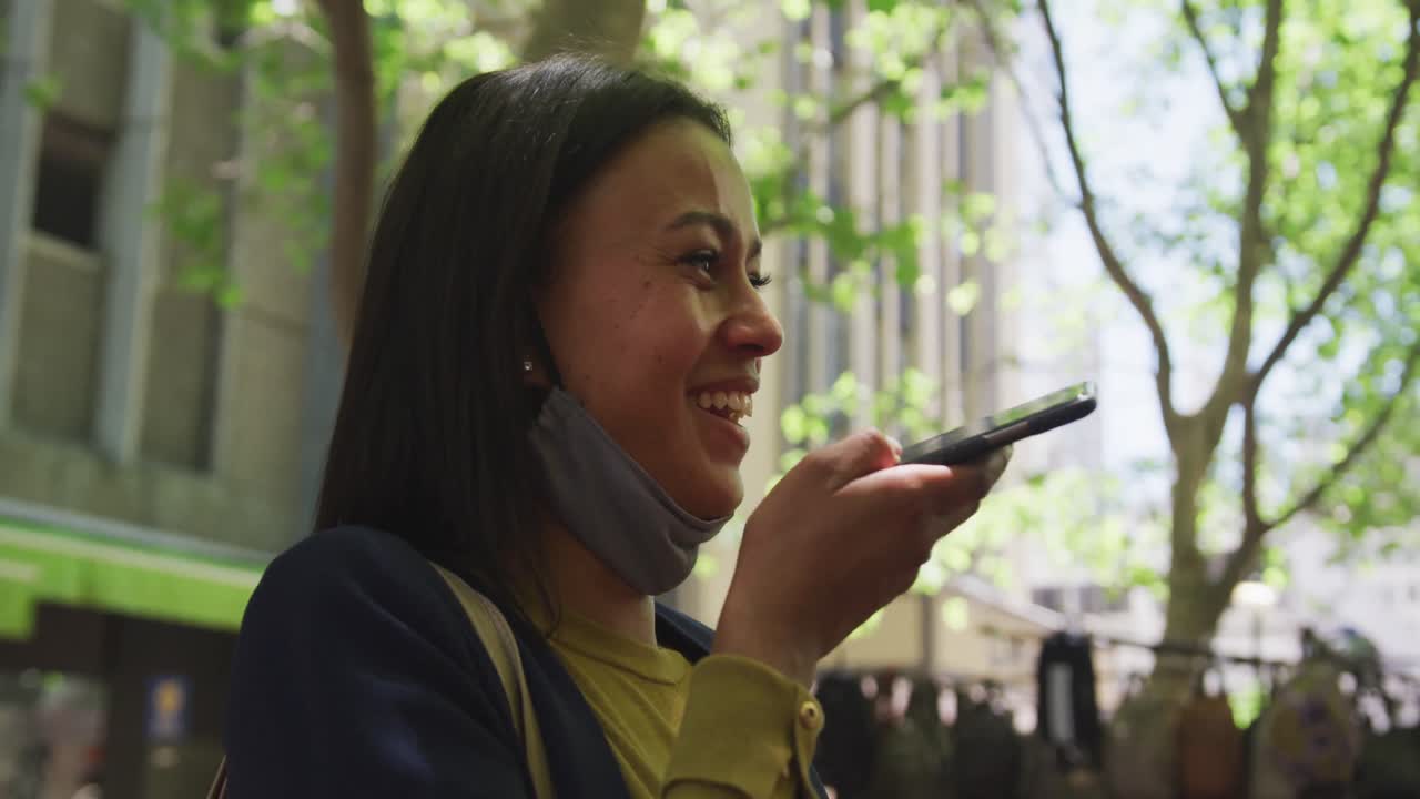 스마트폰으로 이야기하는 얼굴 마스크를 쓴 아프리카계 미국인 여성