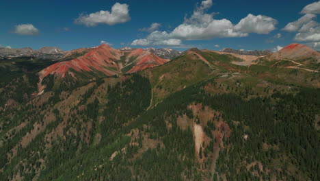 Aerial-cinematic-drone-summer-high-altitude-dirt-road-Silverton-Mountain-Ski-Resort-southern-Colorado-Red-Mountain-Pass-blue-sky-late-morning-stunning-lush-green-blue-sky-partly-cloudy-Rocky-Mountains