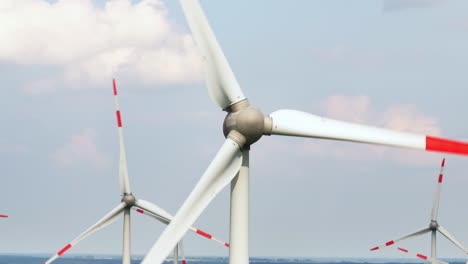 aerial close-up shot circling a wind turbine at a eolic energy farm, sunny day