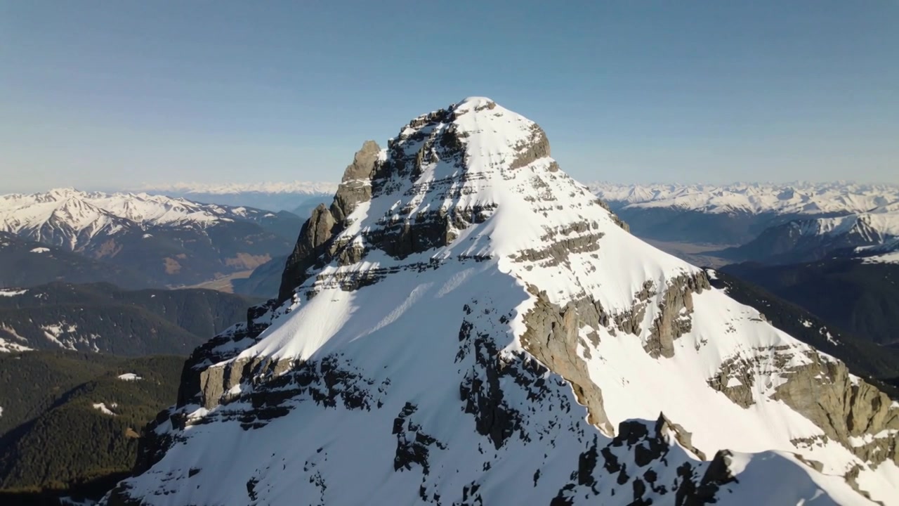 Drone in avvicinamento a una cima montuosa innevata, che rivela pareti rocciose per la mappatura.