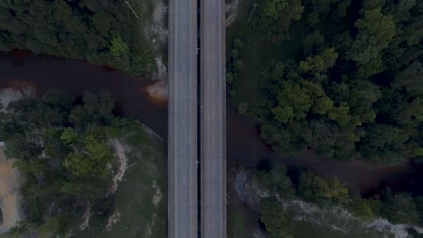 coches que pasan por un puente rural de dos carriles sobre un pequeño río