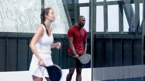 african american man playing padel tennis, focused and ready to hit ball, at indoor court
