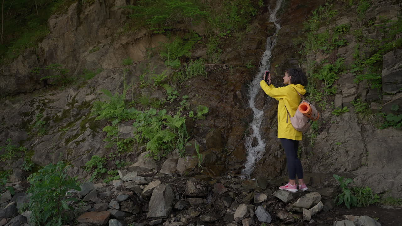 자연 속 의 폭포 의 사진 을 찍는 여자