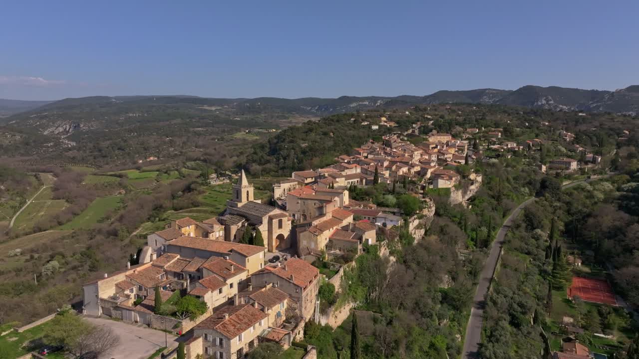 Veduta aerea di Venasque circondata da colline con un'antica chiesa al centro