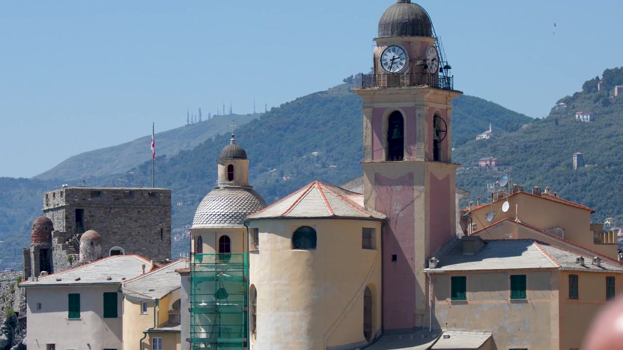 Una lenta panoramica verso l'alto rivela un'antica torre campanaria contro un cielo azzurro limpido.