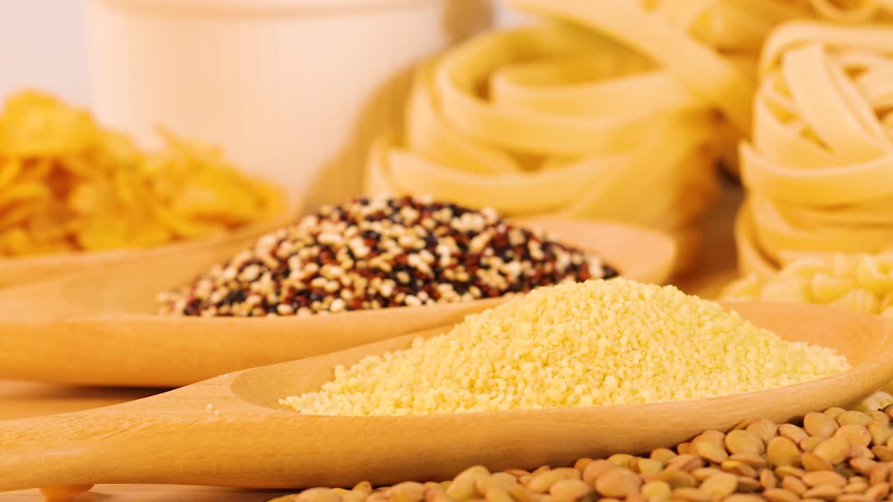 A colorful arrangement of grains, pasta, and bread slices under bright lighting, showcasing diverse textures and colors