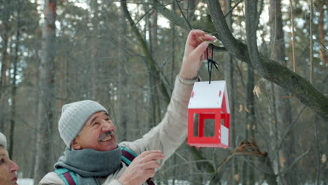 senior couple feeding birds in snowy forest
