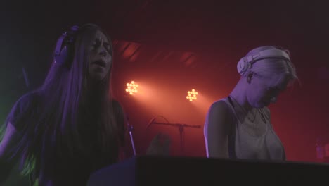 two beautiful young women dj play the music on the mixing console in the nightclub