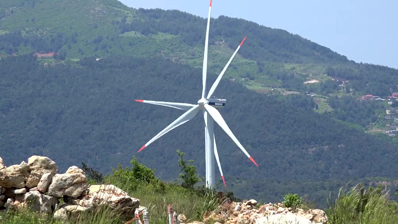 Grande turbina eolica in rotazione su un paesaggio montuoso
