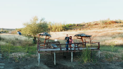 una pareja disfrutando de una copa de vino en un pontón en una zona rural