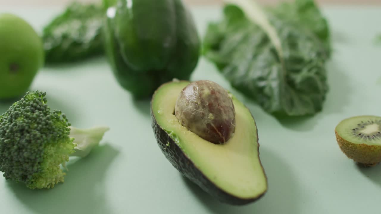 Video di avocado fresco, broccoli, peperone verde e foglie verdi su sfondo verde