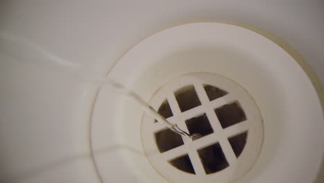 Water-vortex-shot-underwater-extreme-macro-close-up-of-a-bathtub-plug-hole-as-bath-water-empties-with-a-smooth-thin-vortex-above-the-hole