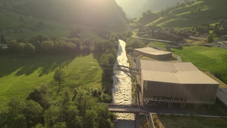 drone-shot-of-a-cabin-entering-the-bottom-station-Grindelwald-Terminal-of-tricable-car-system-at-sunset-in-Grindelwald-Grund-in-Swiss-Alps