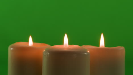 three burning candles on green background