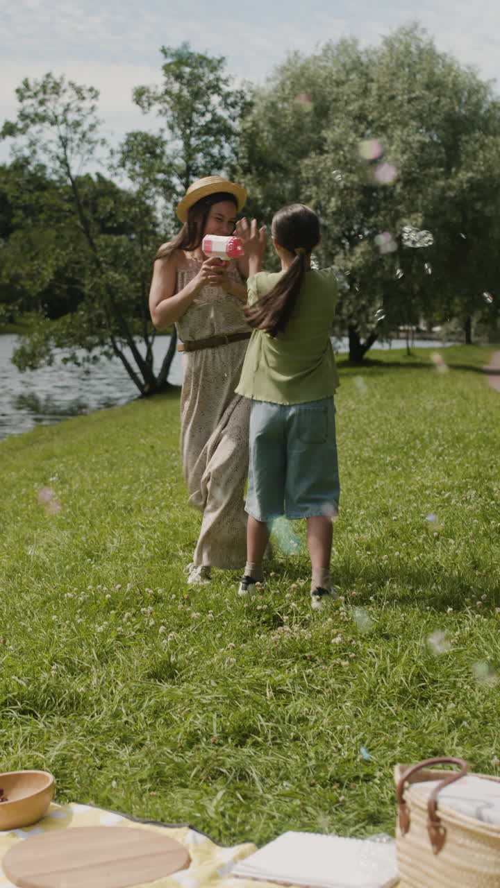 Woman and Girl Playing with Bubbles in the Park