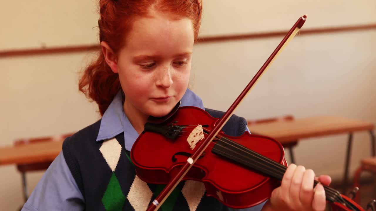 un alumno lindo tocando el violín en el aula