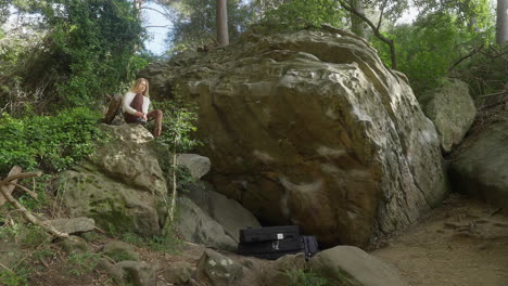 female rock climber sitting putting climbing shoes on in green forest