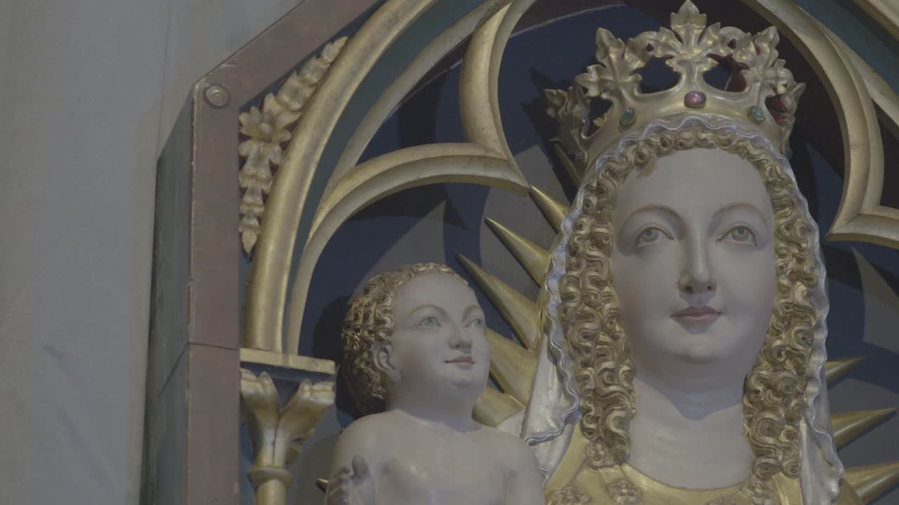Camera pans to the heads of Mother Mary with Jesus on her arm in a relief