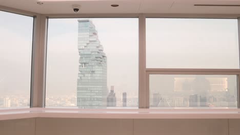 view-of-jagged-modern-architecture-of-the-MahaNakhon,-King-power-skyscraper-through-coffee-shop-window-in-downtown-Bangkok,-the-capital-city-of-Thailand