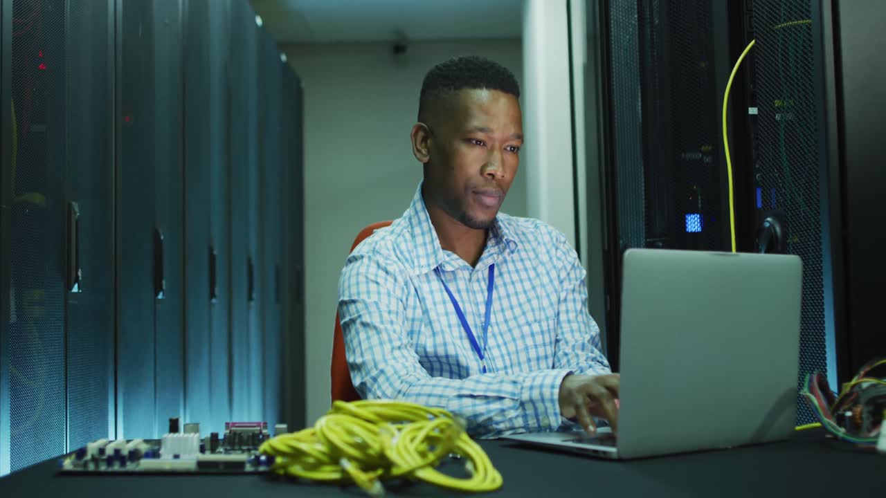 African american male computer technician laptop working in business server room