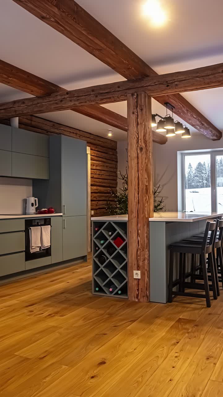 A smooth vertical panning shot reveals the interior of a cozy log cabin, showing the contrast between modern kitchen cabinetry and heavy, rustic exposed wooden beams