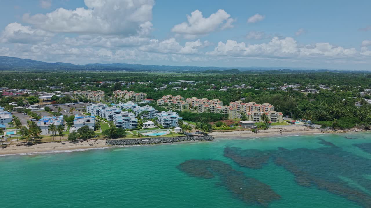 Pan drone shot of Loiza cityscape with sand beach, Atlantic Ocean and blue sky during the day in Puerto Rico, USA