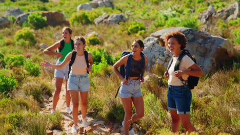 group of female friends with backpacks on vacation on hike through countryside