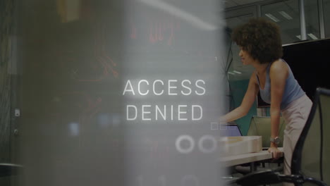 female analyst leaning over cubicle in technology office, showing binary overlay with access denied