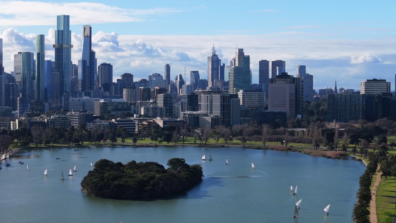Aerial urban drone shot above Albert Park lake in Melbourne with the city skyline in the background