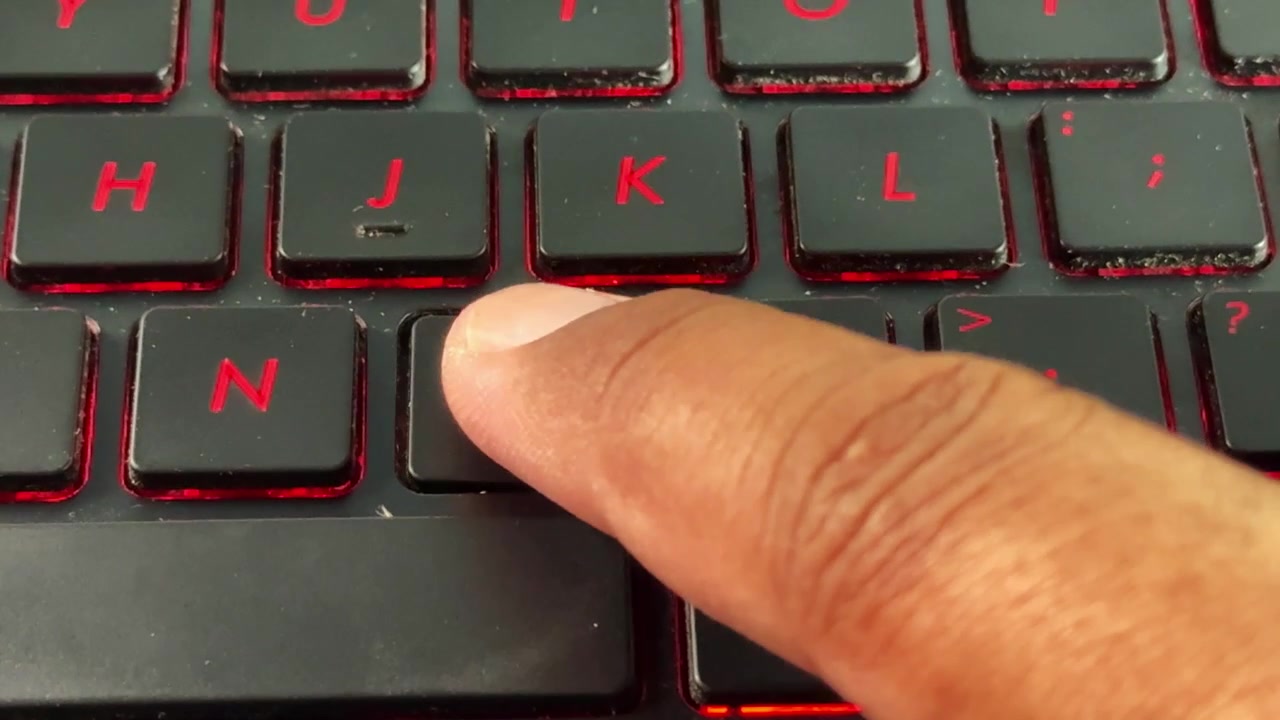 Close-up of keyboard typing with red backlight on "M" button, suitable for cybersecurity, programming, and tech content.