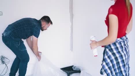 young couple prepares room to paint walls in light flat