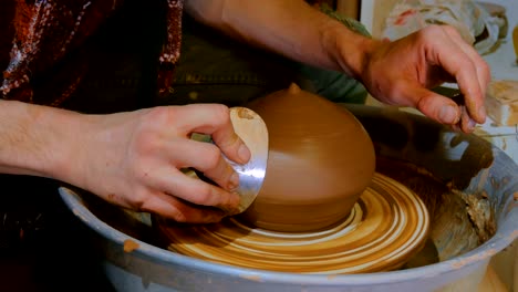 professional potter shaping bowl with special tool in pottery workshop