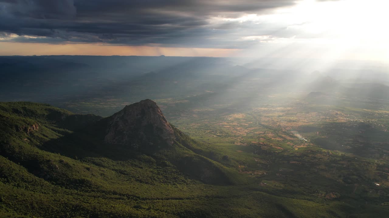 rayos de luz brillando sobre una montaña boscosa