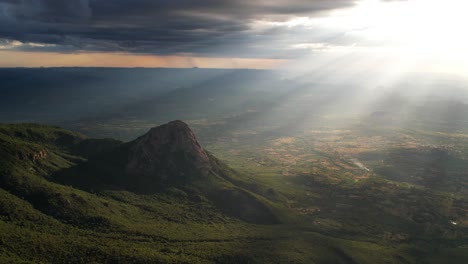 rays of light shining on to a forested mountain